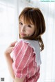 A woman in a red and white checkered shirt leaning against a window.