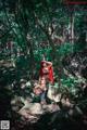 A woman dressed as a red riding hood in the woods.