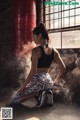 A woman sitting on the ground in front of a punching bag.