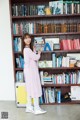 A woman standing in front of a bookshelf full of books.