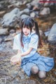 A girl in a school uniform sitting in a stream.