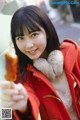 A woman in a red coat holding a popsicle.