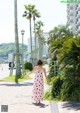 A woman in a red and white dress walking down a sidewalk.