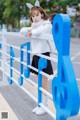 A young girl leaning against a blue and white fence.