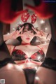 A woman in a red and black lingerie posing for a picture.