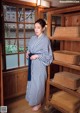 A woman in a blue and white striped robe standing in front of a window.