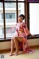 A woman in a pink kimono sitting by a window.