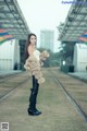 A woman standing on a train track holding a teddy bear.