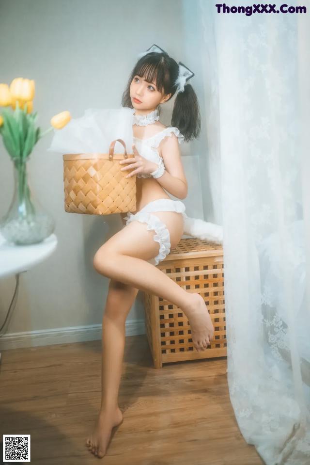 A woman sitting on top of a wooden box holding a basket.