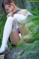 A woman in white stockings is sitting in the grass.