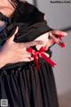 A woman in a black dress holding a red ribbon.