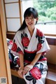 A woman in a kimono sitting on a window sill.