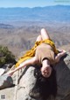 A woman laying on top of a large rock.