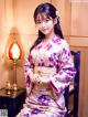 A woman in a purple kimono sitting on a chair.